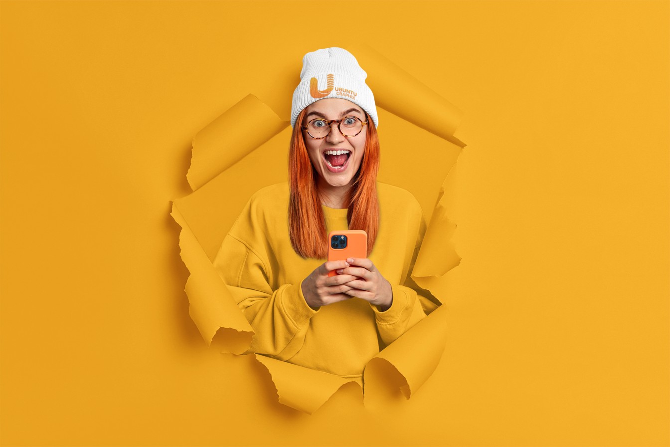 beanie-mockup-of-an-excited-woman-posing-through-a-torn-paper-hole